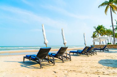 Sahilde deniz ve mavi gökyüzü arka planlı boş bir plaj sandalyesi.