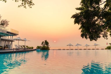 Tatil seyahati konsepti için deniz manzaralı havuzda yüzen şemsiye ve sandalye.