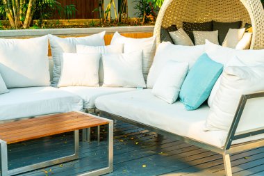 Bahçe sandalyesinde rahat yastıklar ve bahçede masa.