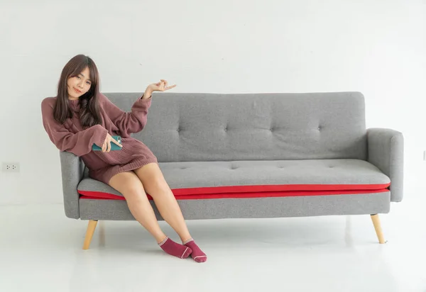 美丽的亚洲女人坐在客厅的沙发上 有复制的空间 — 图库照片
