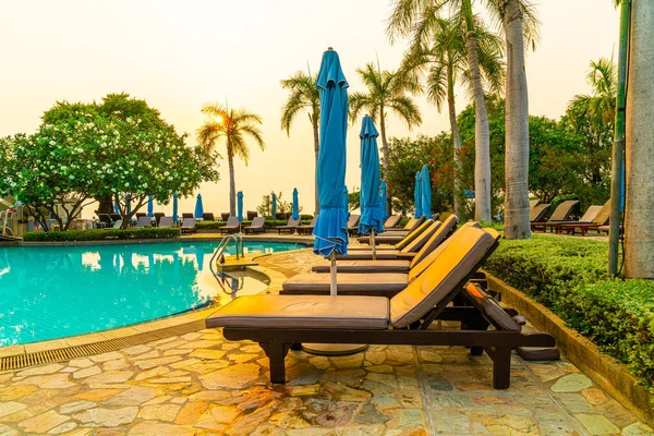 beach chair or pool bed with umbrella around swimming pool at sunset time