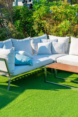 Bahçe sandalyesinde rahat yastıklar ve bahçede masa.