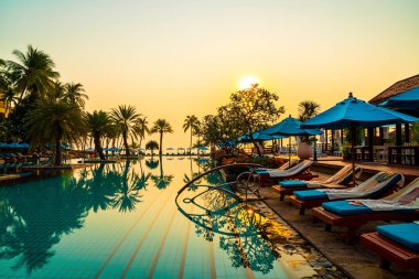 Şemsiye sandalyeli güzel palmiye ağacı gündoğumunda lüks otel tatil beldesinde - tatil ve tatil konsepti