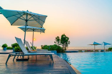 Tatil seyahati konsepti için deniz manzaralı havuzda yüzen şemsiye ve sandalye.