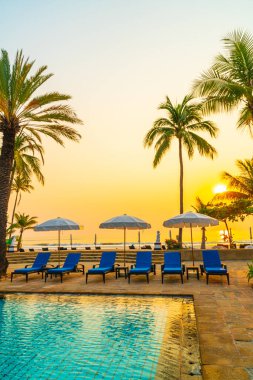 Şemsiye sandalyeli güzel palmiye ağacı gündoğumunda lüks otel tatil beldesinde - tatil ve tatil konsepti