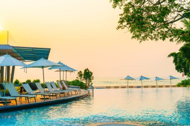 Tatil seyahati konsepti için deniz manzaralı havuzda yüzen şemsiye ve sandalye.