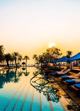 Şemsiye sandalyeli güzel palmiye ağacı gündoğumunda lüks otel tatil beldesinde - tatil ve tatil konsepti