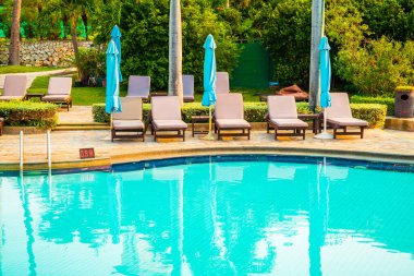 Hindistan cevizi palmiyeli havuz etrafında sandalye ve şemsiye - tatiller ve tatil kavramı