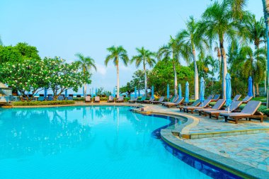 Hindistan cevizi palmiyeli havuz etrafında sandalye ve şemsiye - tatiller ve tatil kavramı