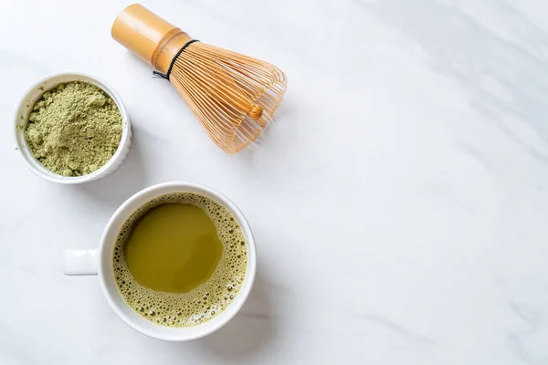 hot matcha green tea cup with green tea powder and bamboo whisk