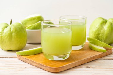 Taze guava suyu bardağı ve ahşap masada taze guava meyvesi.