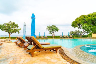 Tayland 'da Pattaya' da deniz plajı geçmişi olan havuz etrafında havuz ve şemsiye.