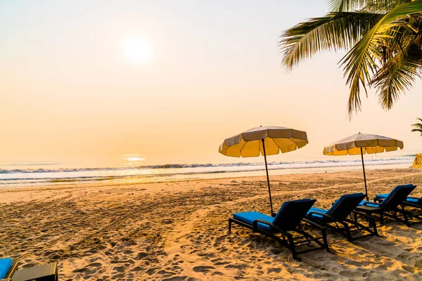 Güneş doğarken palmiye ağacı ve deniz plajı olan şemsiye koltuğu plajı - tatil ve tatil konsepti