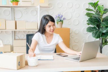 Genç Asyalı kadın, işyerinde dijital tabletle çalışan küçük bir işletme sahibi kuruyor - İnternet satışı, e-ticaret, nakliye konsepti