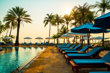 Şemsiye sandalyeli güzel palmiye ağacı gündoğumunda lüks otel tatil beldesinde - tatil ve tatil konsepti