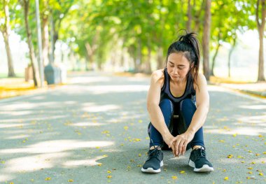 Parktaki egzersizden sonra Asyalı kadın oturuyor ve dinleniyor.
