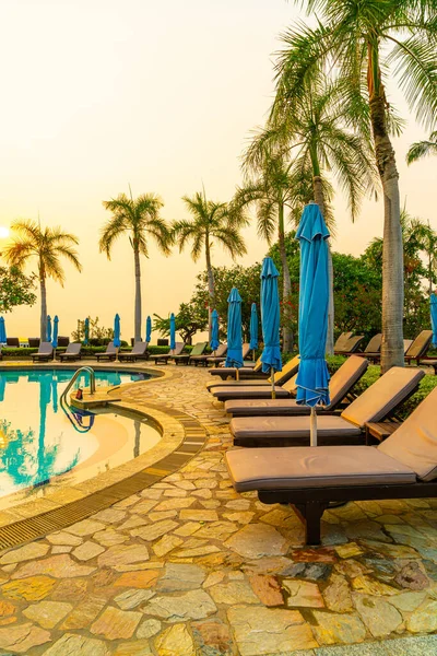 beach chair or pool bed with umbrella around swimming pool at sunset time