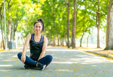 Parktaki egzersizden sonra Asyalı kadın oturuyor ve dinleniyor.