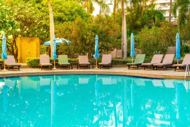 Gün batımında yüzme havuzunda şemsiyeli plaj sandalyesi ya da bilardo yatağı