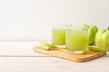 Taze guava suyu bardağı ve ahşap masada taze guava meyvesi.