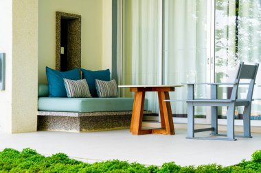 Bahçe sandalyesinde rahat yastıklar ve bahçede masa.