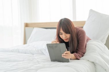 Yatakta tabletle çalışan güzel Asyalı kadınlar