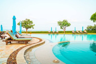 Deniz kenarında yüzme havuzunun etrafında havuz, havuz ve şemsiye.