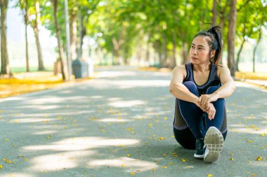 Parktaki egzersizden sonra Asyalı kadın oturuyor ve dinleniyor.