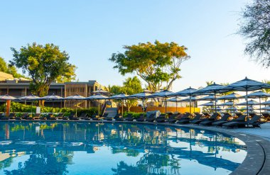 Seyahat tatili konsepti için otel tatil beldesinde yüzme havuzunun etrafında şemsiye ve sandalye.