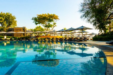 Seyahat ve tatil konsepti için otel tatil beldesinde yüzme havuzunda şemsiyesi ve sandalyesi olan güzel tropik plaj ve deniz.