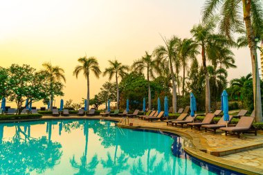 Gün batımında yüzme havuzunda şemsiyeli plaj sandalyesi ya da bilardo yatağı