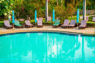 Hindistan cevizi palmiyeli havuz etrafında sandalye ve şemsiye - tatiller ve tatil kavramı