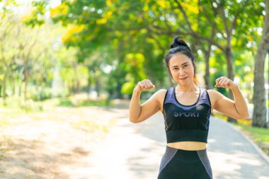 Parkta egzersiz yapmadan önce esneme hareketleri yapan Asyalı kadın.