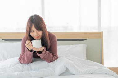 Güzel Asyalı kadınlar sabahları yatakta kahve içerler.