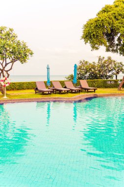 Sandalye havuzu ya da yüzme havuzu etrafında şemsiye olan yatak havuzu