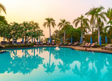 Gün batımında yüzme havuzunda şemsiyeli plaj sandalyesi ya da bilardo yatağı