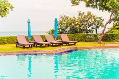 Sandalye havuzu ya da yüzme havuzu etrafında şemsiye olan yatak havuzu