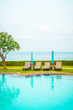 Sandalye havuzu ya da yüzme havuzu etrafında şemsiye olan yatak havuzu