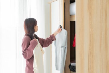 beautiful Asian women choosing cloths in a room