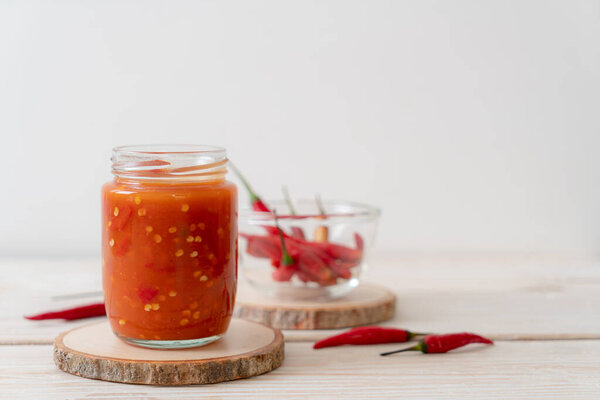 chilli or chilli sauce in bottle and jar on wwod background