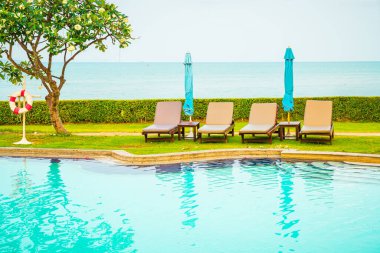Sandalye havuzu ya da yüzme havuzu etrafında şemsiye olan yatak havuzu