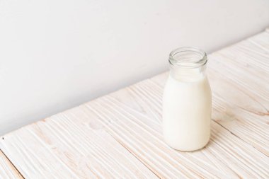 Ahşap arka planda şişede taze süt