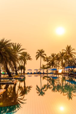 Şemsiye sandalyeli güzel palmiye ağacı gündoğumunda lüks otel tatil beldesinde - tatil ve tatil konsepti