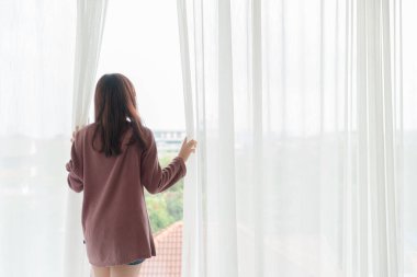 Güzel Asyalı kadınlar sabah perdeyi açar.