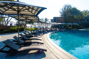 Seyahat ve tatil konsepti için otel otelinde yüzme havuzunun etrafında güzel bir havuz ve şemsiye.