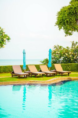 Sandalye havuzu ya da yüzme havuzu etrafında şemsiye olan yatak havuzu