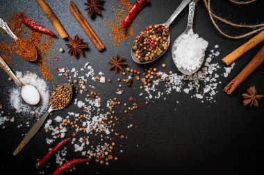 Siyah arkaplanda kaşık ve kopyalama alanı olan baharatlar ve otlar.
