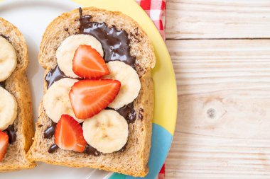 Kahvaltıda taze muz, çilek ve çikolatalı tam buğday ekmeği.