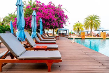 Sandalye havuzu ya da yüzme havuzu etrafında şemsiye olan yatak havuzu