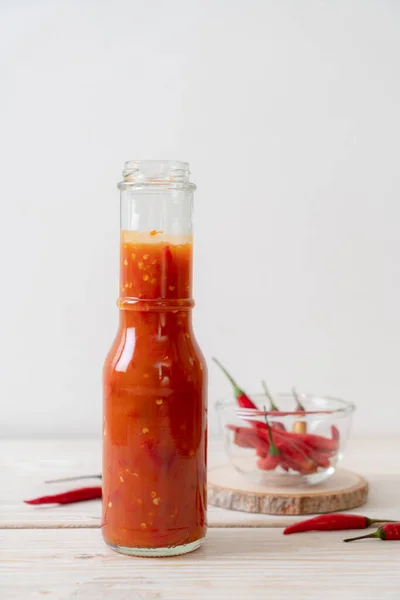 chilli or chilli sauce in bottle and jar on wwod background